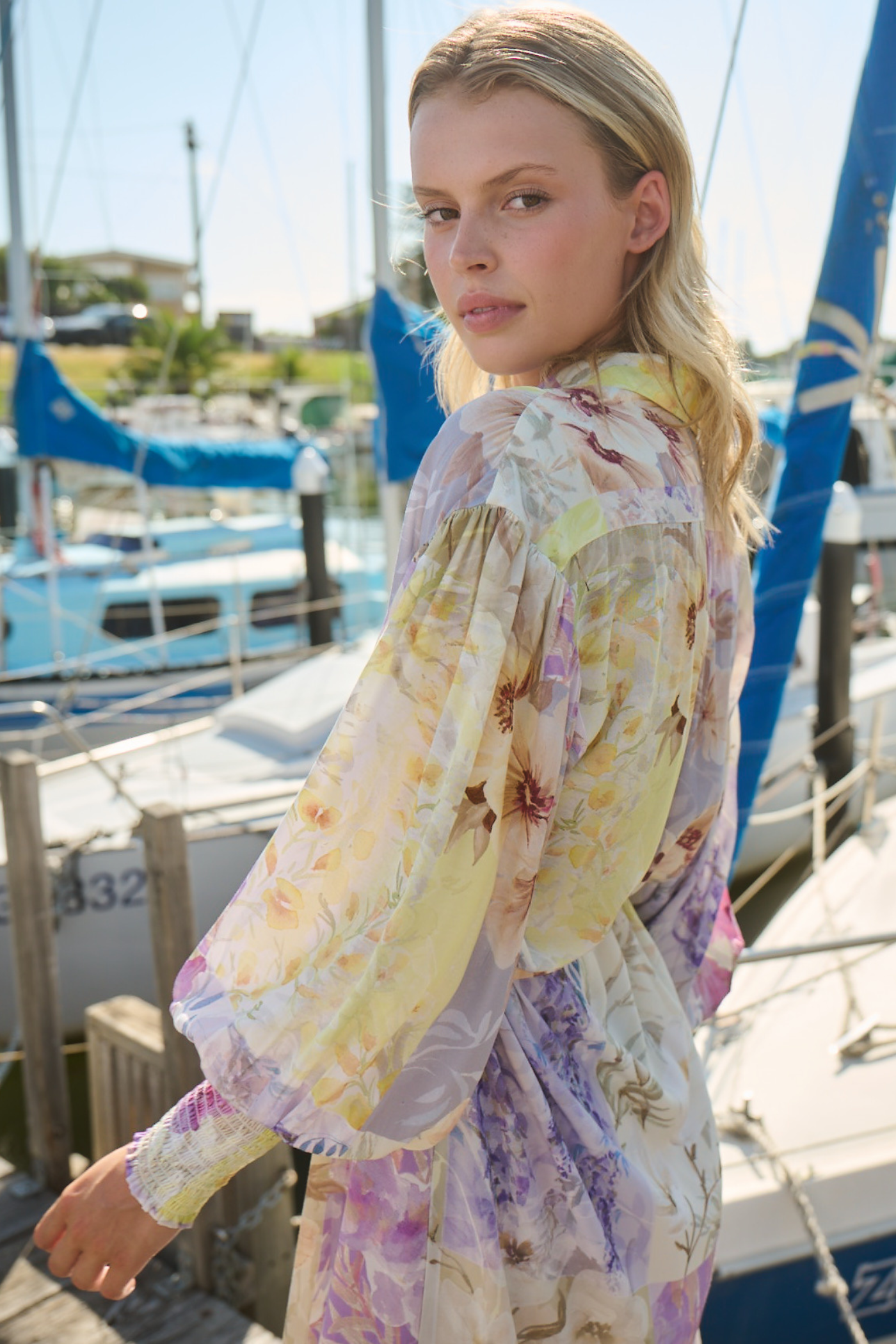 woman posing wearing long sleeve dress by boats