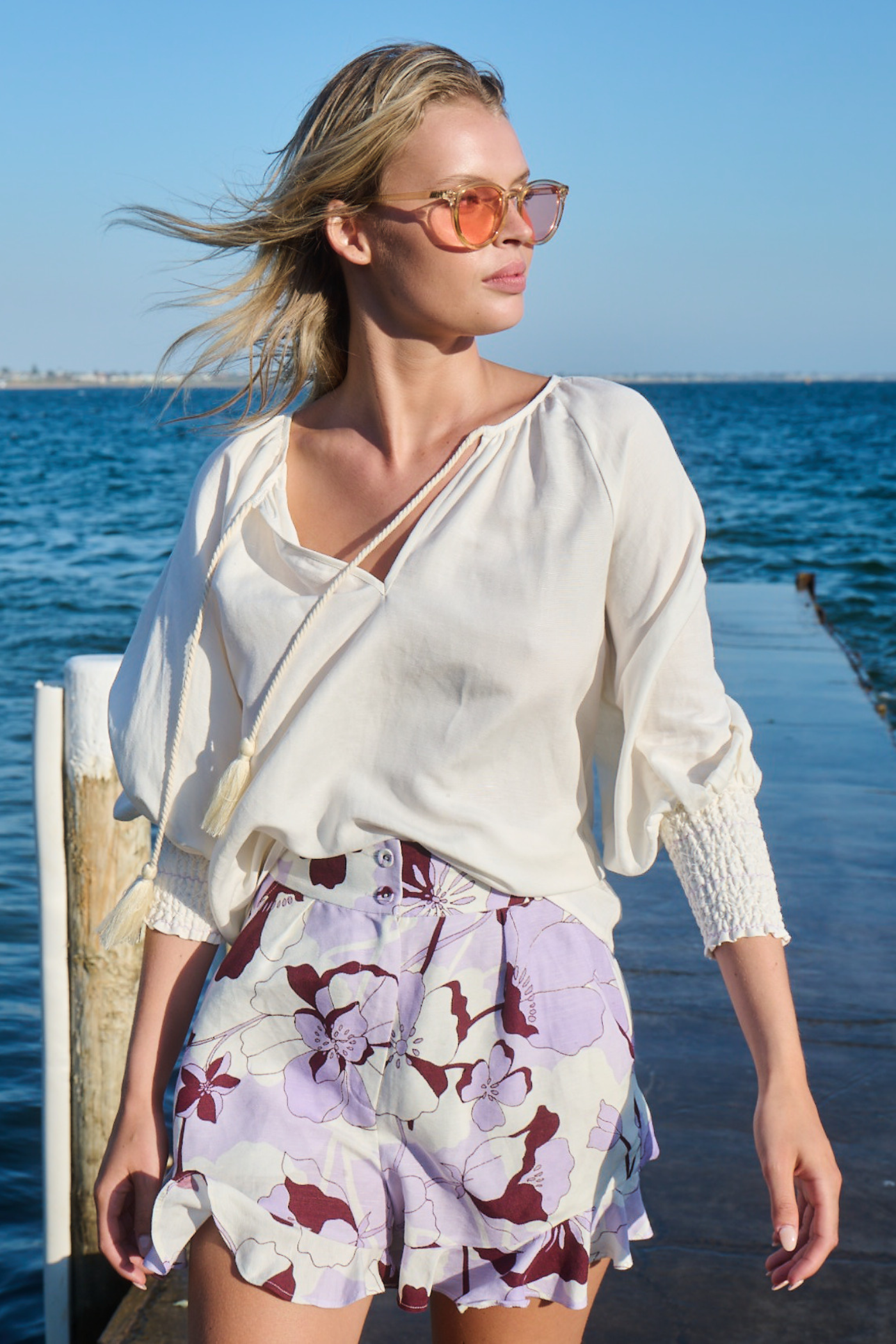 blonde girl wearing pink sunglasses and lilac shorts