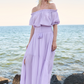 Model on rocks posing in long purple dress